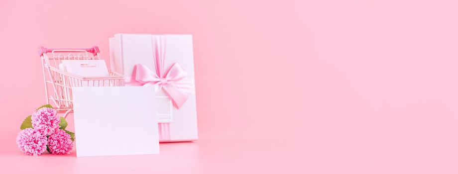 Mother's Day holiday gift design concept, pink carnation flower bouquet with wrapped gift box isolated on pink background, copy space.