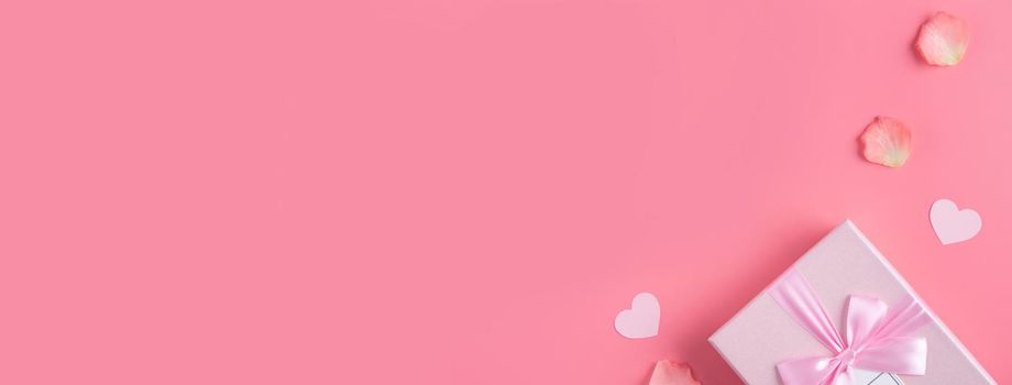 Valentine's Day design concept background with pink petals and gift box on pink background