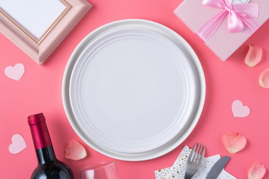 Empty white plate with gift and rose petals for Valentine's Day special holiday dating meal concept.