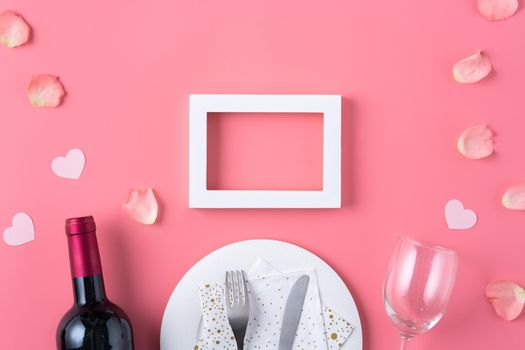 Empty white plate with gift and rose petals for Valentine's Day special holiday dating meal concept.