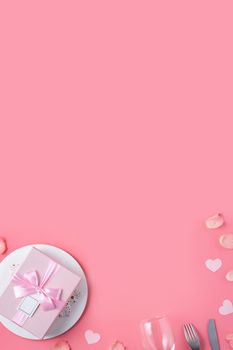 Empty white plate with gift and rose petals for Valentine's Day special holiday dating meal concept.