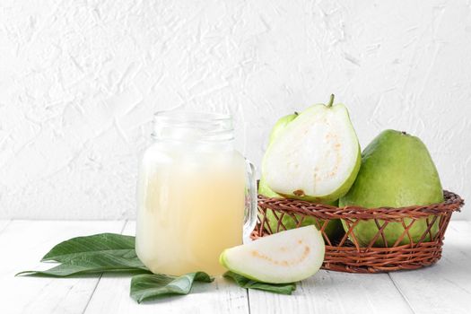 Delicious beautiful guava fruit with fresh juice set isolated on bright white wooden table background, close up.