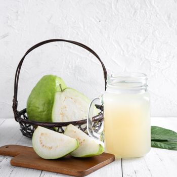 Delicious beautiful guava fruit with fresh juice set isolated on bright white wooden table background, close up.