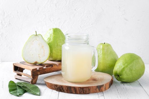 Delicious beautiful guava fruit with fresh juice set isolated on bright white wooden table background, close up.