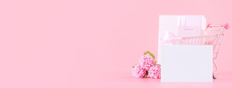 Mother's Day holiday gift design concept, pink carnation flower bouquet with wrapped gift box isolated on pink background, copy space.