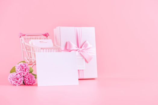 Mother's Day holiday gift design concept, pink carnation flower bouquet with wrapped gift box isolated on pink background, copy space.