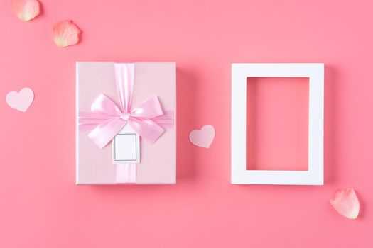 Valentine's Day design concept background with pink petals and gift box on pink background