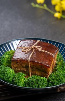Dong Po Rou (Dongpo pork meat) in a beautiful blue plate with green broccoli vegetable, traditional festive food for Chinese new year cuisine meal, close up.