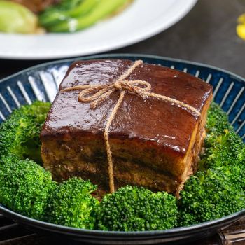 Dong Po Rou (Dongpo pork meat) in a beautiful blue plate with green broccoli vegetable, traditional festive food for Chinese new year cuisine meal, close up.