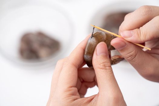Woman deveins shrimp and pull out intestinal tract line when cooking shrimp.