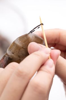 Woman deveins shrimp and pull out intestinal tract line when cooking shrimp.