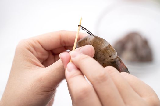 Woman deveins shrimp and pull out intestinal tract line when cooking shrimp.