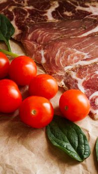 Meat slices and cherry tomatoes. Ingredients for sandwich and bruschetta. Cooking snacks. Spinach leaves. Vertical photo