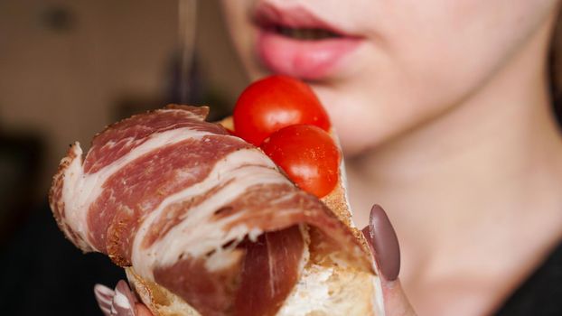 Close-up photo. Woman bites fresh bruschetta with cherry tomato. Delicious Italian appetizer.