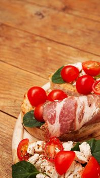 Italian appetizer. Bruschetta on a wooden board on a wooden rustic background. Delicious fresh appetizer with tomatoes and bacon