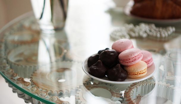 Macaroons on a glass table. Sweets for breakfast. Sunny photo. Romantic breakfast concept