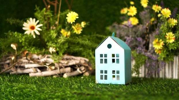 Cardboard blue house on a background of green spring grass. Village house concept. Loan or purchase of a country house
