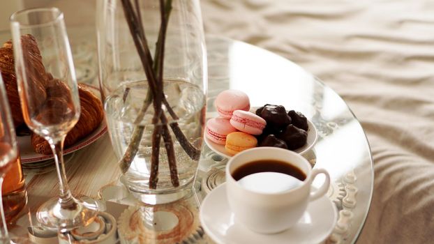 Glass table with a cup of coffee, sweet macaroons. A festive and romantic photo. Morning after date