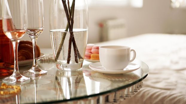 Glass table with a cup of coffee, sweet macaroons. A festive and romantic photo. Morning after date