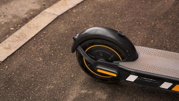Close-up photo of the rear wheel of an electric scooter against the background of asphalt