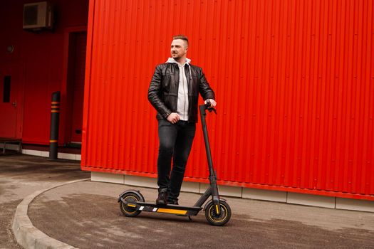 Young attractive man on electric scooter over red background. Urban transport