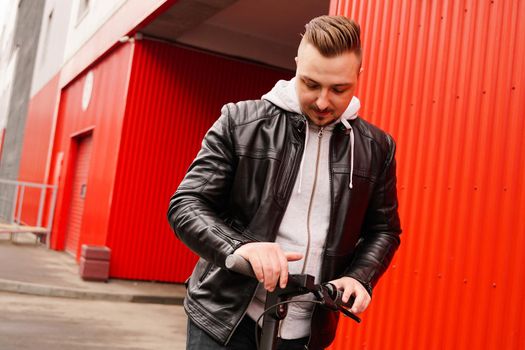 Young attractive man on electric scooter over red background. Urban transport