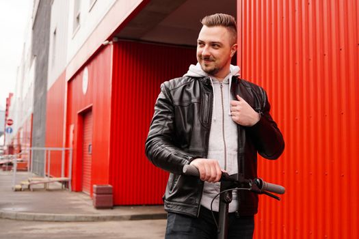 Young attractive man on electric scooter over red background. Urban transport