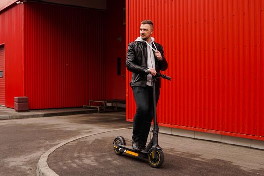 Young attractive man on electric scooter over red background. Urban transport