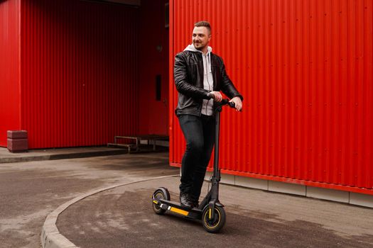 Young attractive man on electric scooter over red background. Urban transport