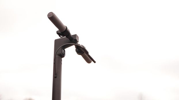 Close-up of the steering wheel of an electric scooter outside. The beginning of the spring season for scooter riding.