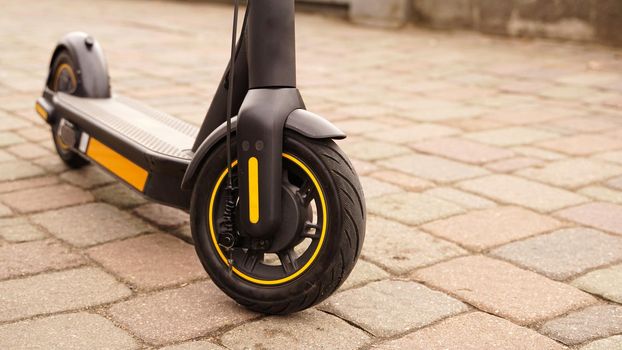 A close-up of the front wheel of an electric scooter against a tile backdrop. Photo on the street