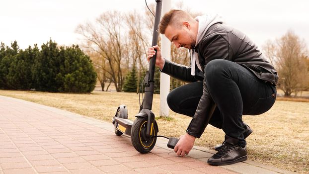 A man pumps air into the wheel of an electric scooter using a special device. Photo outside. A flat tire while driving.