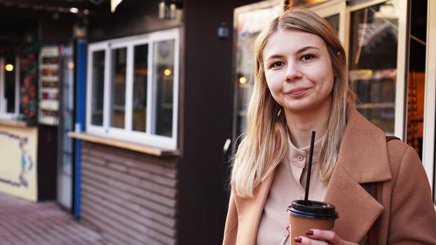 Young blonde with a cup of coffee. Woman at the food court. Lifestyle photo. Beautiful woman drinking coffee