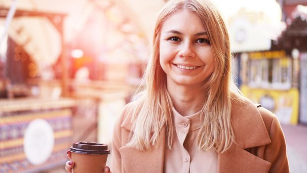 Young blonde with a cup of coffee. Woman at the food court. Lifestyle photo. Beautiful woman drinking coffee. Glare of the sun