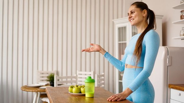 A woman nutritionist talks about the benefits of a healthy diet in the kitchen. Side view. Healthy lifestyle vlogging or seminar concept