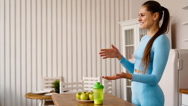 A woman nutritionist talks about the benefits of a healthy diet in the kitchen. Side view. Healthy lifestyle vlogging or seminar concept