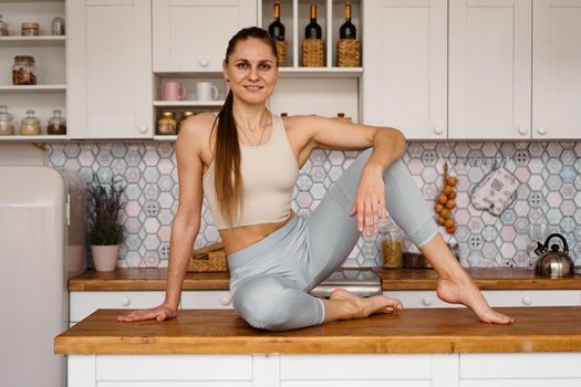 Athletic woman in sportswear posing on the table top. The concept of beauty, health, proper nutrition. Woman smiling and looking at the camera