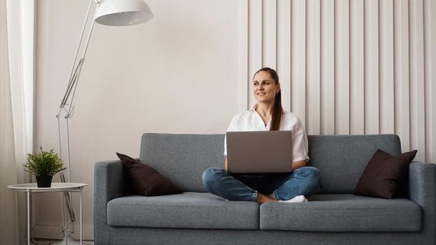 Woman working on laptop from home or student studying from home or freelancer. Modern business woman in a white shirt and jeans.