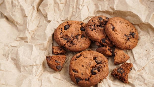 Flatview of handcrafted chocolate cookies with chocolate chips on baking paper. Natural handmade organic snakes for healthy breakfast