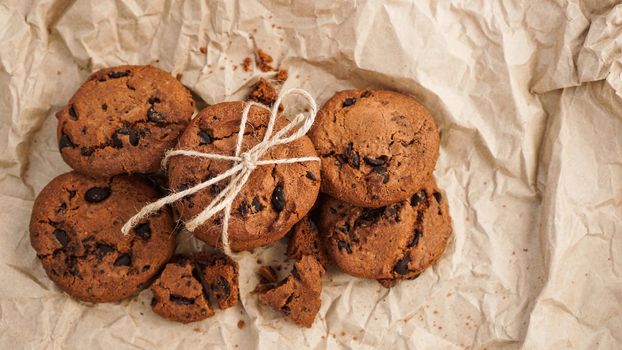 Flatview of handcrafted chocolate cookies with chocolate chips on baking paper. Natural handmade organic snakes for healthy breakfast