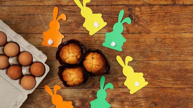 Homemade muffin with with paper rabbits. Muffin and eggs on a wooden background. Easter dessert concept