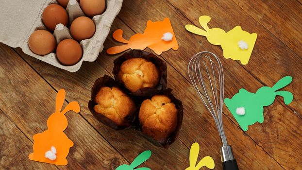 Homemade muffin with with paper rabbits. Muffin and eggs on a wooden background. Easter dessert concept