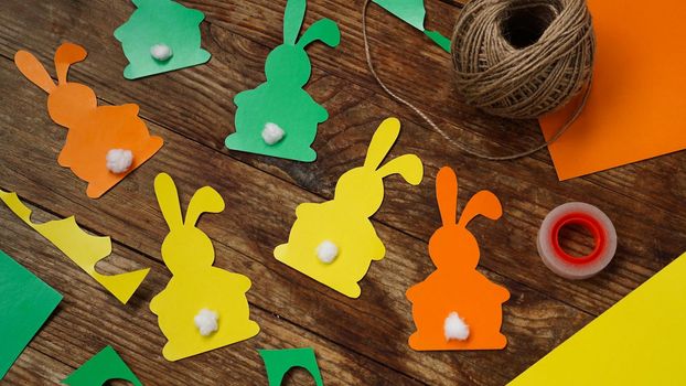 Easter bunnies made of paper on a wooden background. Create a decor for easter. DIY Easter garland making