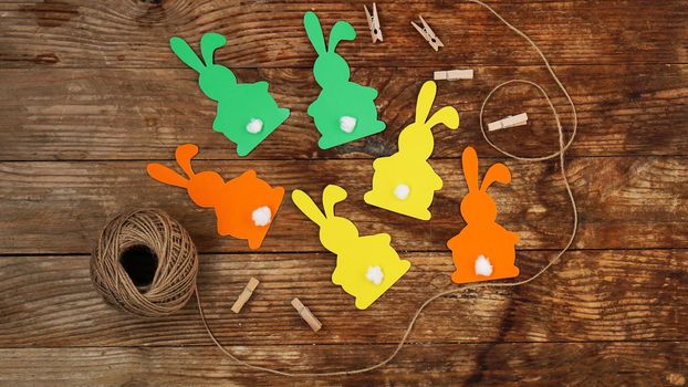 Easter bunnies made of paper on a wooden background. Create a decor for easter. DIY Easter garland making