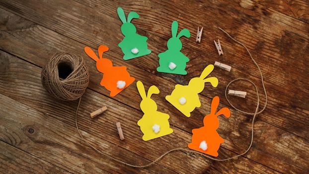 Easter bunnies made of paper on a wooden background. Create a decor for easter. DIY Easter garland making