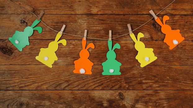Easter background. Garland of paper rabbits on a wooden background. Bunny background. Spring decor with copy space