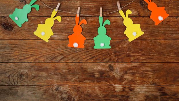 Easter background. Garland of paper rabbits on a wooden background. Bunny background. Spring decor with copy space