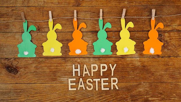 Happy Easter background. Garland of paper rabbits on a wooden background. Bunny background. Spring decor