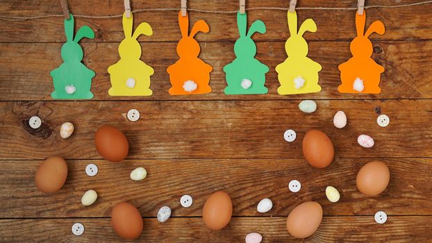 Happy Easter background. Garland of paper rabbits on a wooden background. Bunny background with eggs. Spring decor with copy space