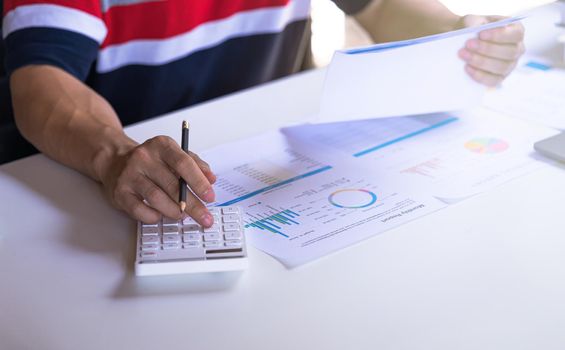 Businessman using calculator and holding paperwork, business profits document. Financial and tax systems concept.